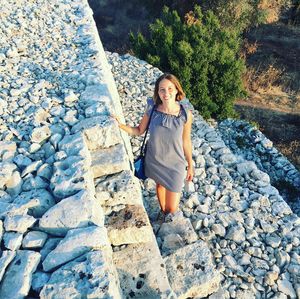 Portrait of smiling young woman standing on rock