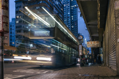 Illuminated street amidst buildings in city at night