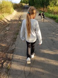 Rear view of woman with dog walking on footpath