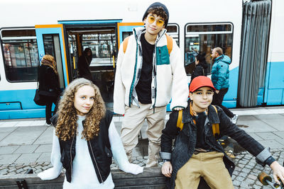 Portrait of male and female friends against tram in city