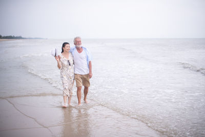 Senior couple walk on the beach with love and care