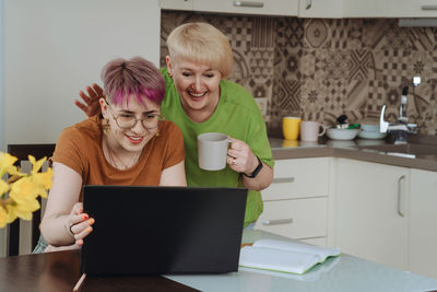 Elderly mother and daughter greet their loved ones by video call on laptop