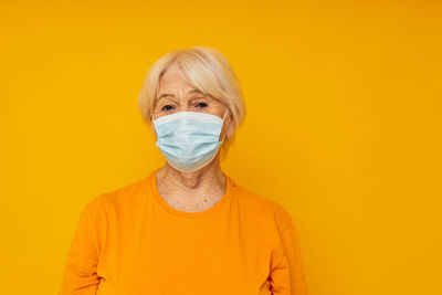 Portrait of young woman against yellow background