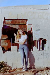 Portrait of young woman standing against wall