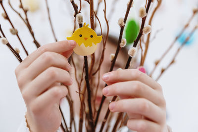 The girls glue the chick sticker onto the willow branches.