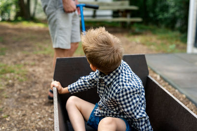 A man pulling a wooden wagon with his son.