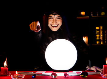 Portrait of smiling young woman on illuminated table
