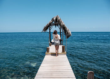 Rear view full length of young woman on pier amidst sea