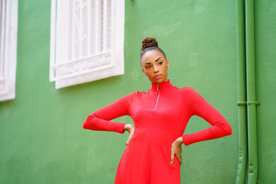 Portrait of young woman standing against wall