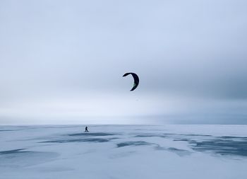 Minimalist picture with lonely kite surfer on frozen lake in winter