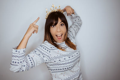 Portrait of young woman standing against gray background