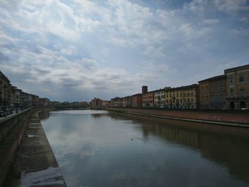 Bridge over river by buildings in city against sky