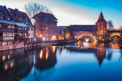 Reflection of illuminated bridge over river in city