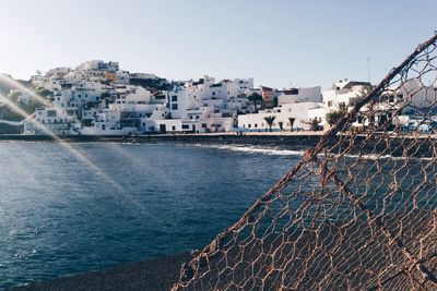 Damaged fence by sea during sunny day