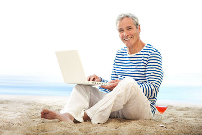Young man using mobile phone while sitting on beach
