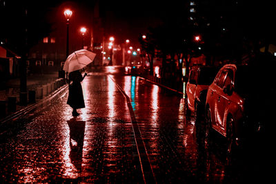 Man walking on wet street during rainy season at night