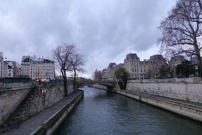 Bridge over river by buildings against sky in city