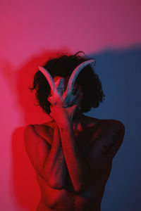 Young man covering face standing against wall