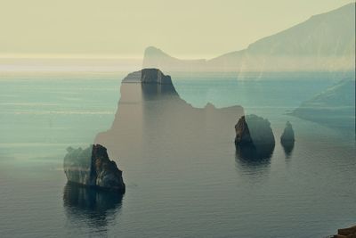 Scenic view of sea against sky, rocky coastline double exposure