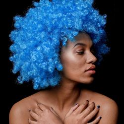 Close-up portrait of shirtless young woman against black background