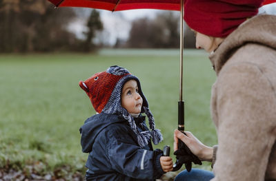 Mother with baby girl holding umbrella on field