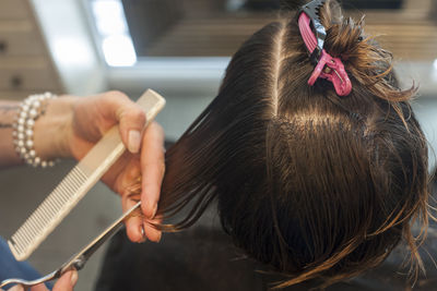 Close-up of hairdresser cutting hair of man