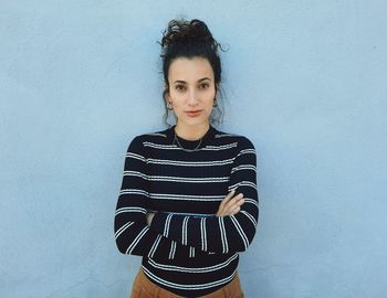 Portrait of young woman standing against wall