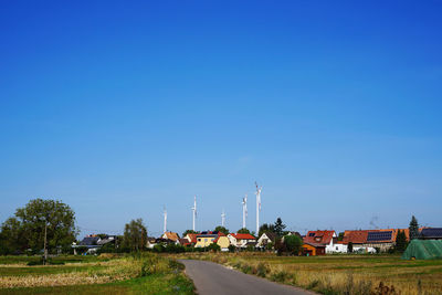 Road amidst field against blue sky