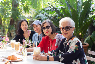 Asian senior woman and adult daughter drinking coffee at cafe outdoor.