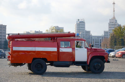 Red car on street against buildings in city