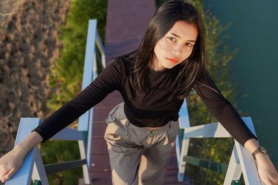 Portrait of beautiful young woman standing against railing