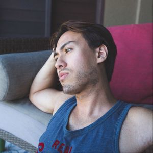 Thoughtful young man sitting by sofa at home