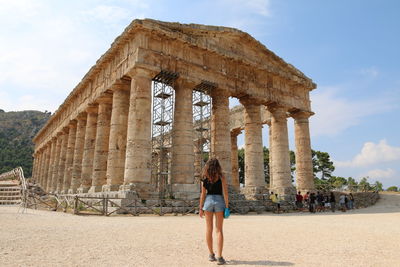 Woman standing by historical building against sky