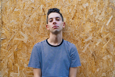 Portrait of young man standing against wall