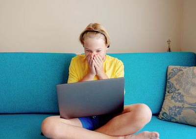 Boy using laptop while sitting on sofa at home