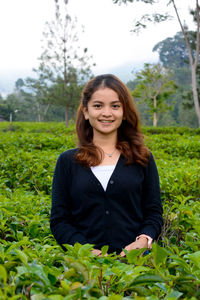 
a beautiful woman in black, she is standing among the tea leaves