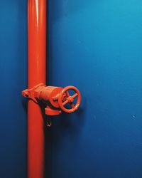 Red pipeline with safety valve against blue wall