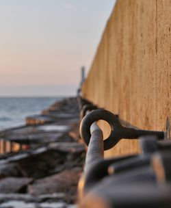 Close-up of rusty metal on beach against clear sky