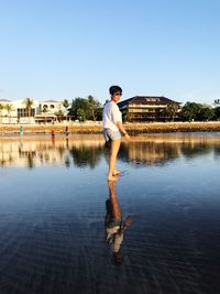 Woman wading in sea against clear blue sky