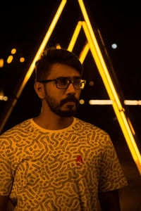 Portrait of young man standing against black background