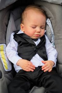 Little baby dressed for baptism sleeping in his stroller