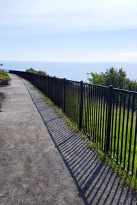 Footpath by railing against sky