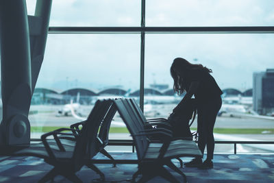 Side view of woman sitting on chair in airport