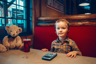 Portrait of boy with toy sitting at restaurant