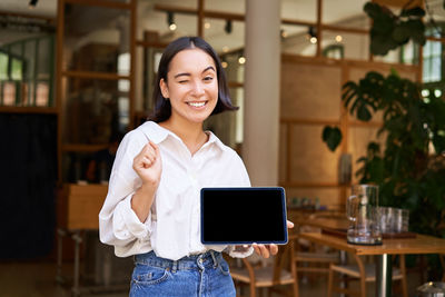 Portrait of young woman using digital tablet in cafe