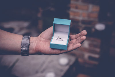 Cropped hand of man holding engagement ring box