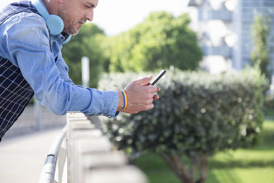 Side view of man using mobile phone in city