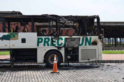 View of abandoned bus on street in city against sky