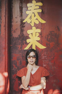 Asian woman wearing red shirt standing pose red wooden door background 