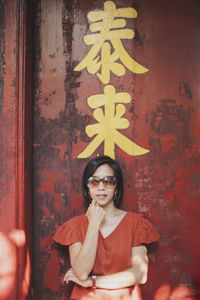 Portrait of smiling young woman standing against wall